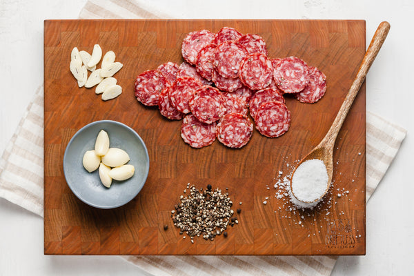 View of all raw ingredients in Saucisson Sec nitrate free salami arranged on a cutting board.