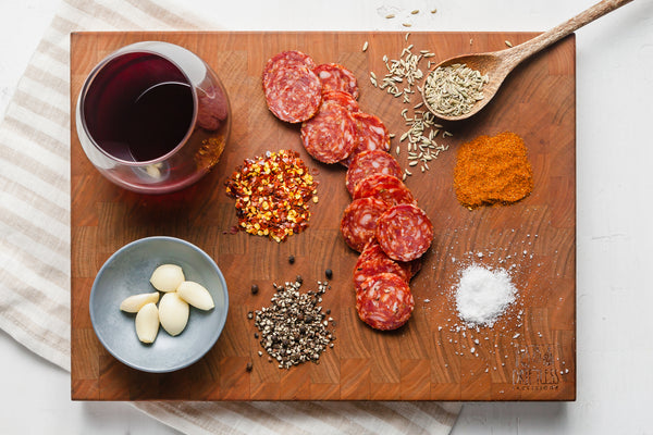 View of all raw ingredients in spicy finnochiona nitrate free salami arranged on cutting board.